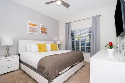 a white bedroom with a bed and a window at 3151LS TOWNHOUSE 4 BEDROOMS & 3 BATHROOMS + POOL in Kissimmee