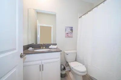 a bathroom with a toilet and a sink and a mirror at 2825PA VILLA 5 BED/5 BA (SANITIZED) in Kissimmee