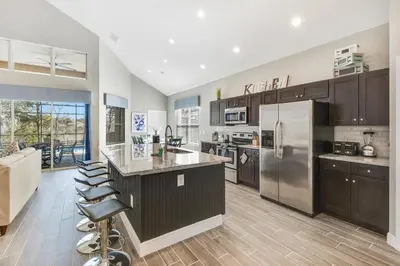 a kitchen with stainless steel appliances and wooden cabinets at Ohana House at Windsor Hills, Disney World Luxury Rental in Orlando