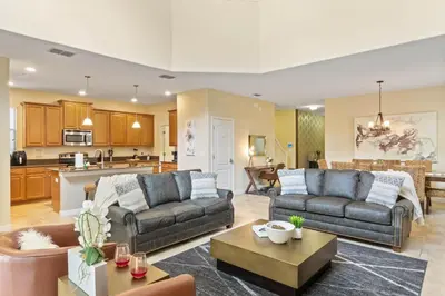 a living room with two couches and a kitchen at Spacious Vacation Home with Pool & Jacuzzi Near Disney in Kissimmee