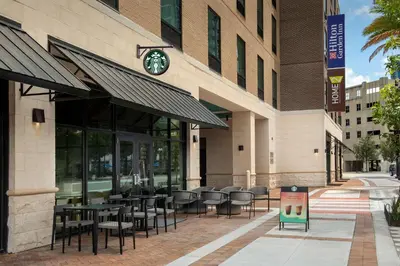 a restaurant with tables and chairs outside of a building at Hilton Garden Inn Orlando Downtown in Orlando
