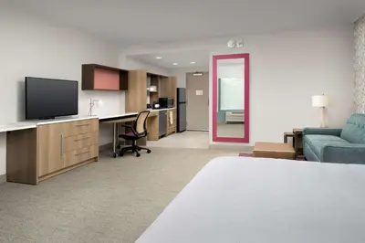 a living room with a couch and a desk with a television at Home2 Suites by Hilton Orlando Downtown, FL in Orlando