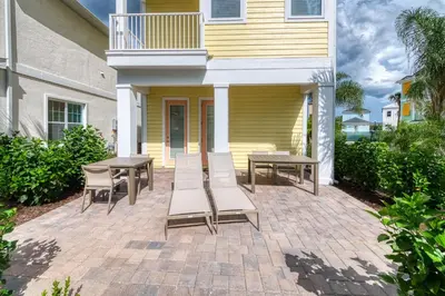 a patio with chairs and tables in front of a house at Vibrant Cottage Near Disney With Margaritaville Resort & Island H20 Waterpark Access- 3000Sp in Orlando