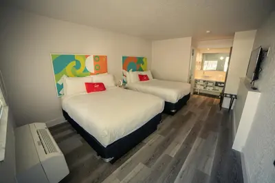 a bedroom with two beds and a television in it at Travelodge by Wyndham Orlando Lake Buena Vista South in Kissimmee
