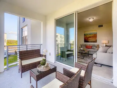 a balcony with wicker chairs and a living room at Modern Condo near Disney Foosball Water Park in Kissimmee