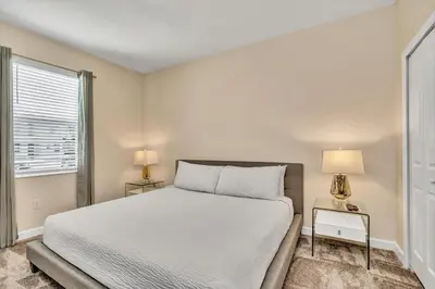 a bedroom with a white bed and two lamps at VILLA wPrivate Pool & Game Room near Disney in Kissimmee
