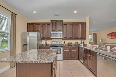 a large kitchen with wooden cabinets and granite counter tops at Modern Villa wPrivate Pool and Air Hockey Table in Orlando