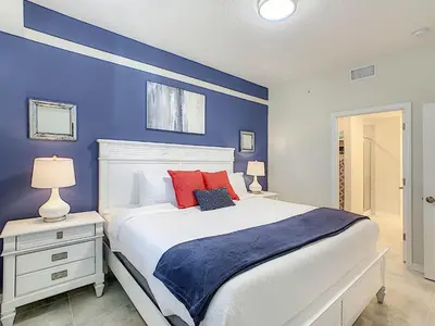 a blue bedroom with a white bed with red pillows at 3131 Paradox Cir Unit 203 in Kissimmee