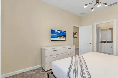 a white bedroom with a bed and a dresser at 4520 Target Blvd in Kissimmee