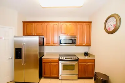 a kitchen with wooden cabinets and a stainless steel refrigerator at Vista Cay at Epic Universe - Standard 3 bedroom penthouse in Orlando