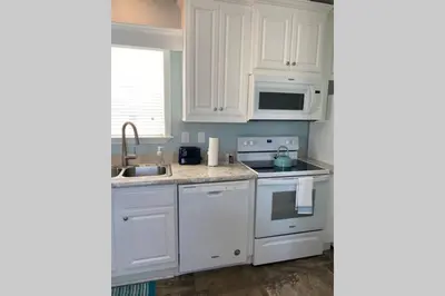 a kitchen with white cabinets and a sink and a microwave at Cozy Tiny Home Near Disney World & Orlando Parks! in Kissimmee