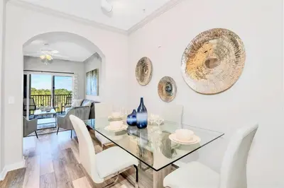 a dining room with a glass table and white chairs at Inviting 3BR Condo with Private Patio - Near Disney in Orlando