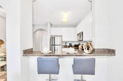 a kitchen with white cabinets and blue chairs at Inviting 3BR Condo with Private Patio - Near Disney in Orlando