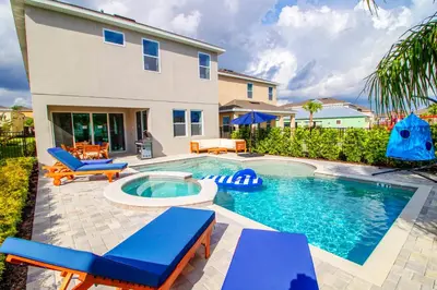 a swimming pool with blue chairs and a house at Encore Resort 6 Bedroom Vacation Home with Pool (2102) in Orlando