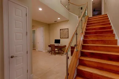 a hallway with stairs and a desk in a house at Mickeys Atlantis - Luxury 8BR Mansion Oasis Pool Hot Tub Outdoor Kitchen Home Theater, Game Room & More! 2 Miles to Disney in Orlando