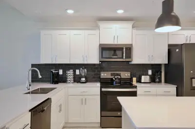 a kitchen with white cabinets and black appliances at Beautiful apartment in lux Storey Lake community 10 miles to Disney! in Kissimmee