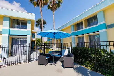 a table and chairs with an umbrella in front of a building at Garnet Inn & Suites, Orlando in Orlando
