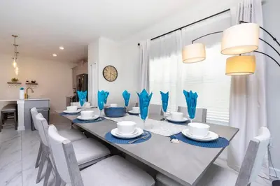 a dining room with a table and chairs and a clock at Stunning 5 Bd w/ Pool Close to Disney 2905 in Kissimmee