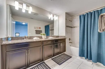 a bathroom with a sink and a tub and a mirror at 7 Mi Walt Disney World! Family Gem with Private Pool in Kissimmee