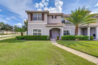 a house with a palm tree in the yard at 7 Mi Walt Disney World! Family Gem with Private Pool in Kissimmee