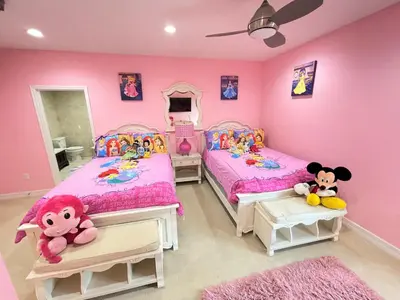 two beds in a girls bedroom with pink walls at Mickeys Getaway - CUSTOM 8BR Luxurious Retreat Pool Hot Tub Theater RM Gym! Outdoor Kitchen 2 Miles to Disney in Orlando