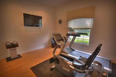 a room with a gym with a treadmill and a television at Mickeys Getaway - CUSTOM 8BR Luxurious Retreat Pool Hot Tub Theater RM Gym! Outdoor Kitchen 2 Miles to Disney in Orlando