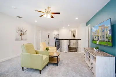 a living room with two chairs and a ceiling fan at 9 Bed Storey Lake Resort Game Room Pool home in Kissimmee