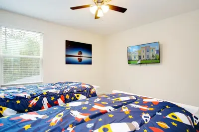 a bedroom with two beds and a ceiling fan at 9 Bed Storey Lake Resort Game Room Pool home in Kissimmee