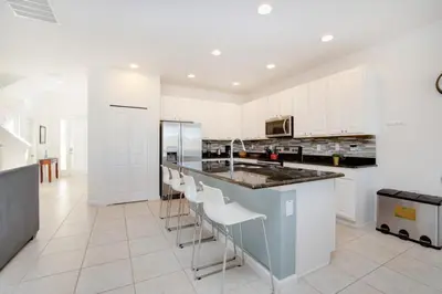 a kitchen with white cabinets and a island with bar stools at 5 Bed 5 Bath in 5 Star Resort Near Disney! home in Kissimmee