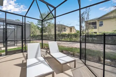 two white chairs sitting on a screened porch with glass walls at Boutique Style Home Near Disney! home in Kissimmee
