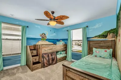 a bedroom with a bed with a painting of the ocean at Storey Lake Resort 9 Bed Game Theater Room home in Kissimmee