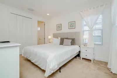 a white bedroom with a large bed and a window at Beautiful Home Near Disney with Private Pool! villa in Orlando