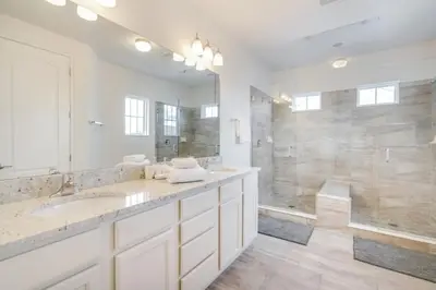 a white bathroom with two sinks and a shower at Beautiful Home Near Disney with Private Pool! villa in Orlando