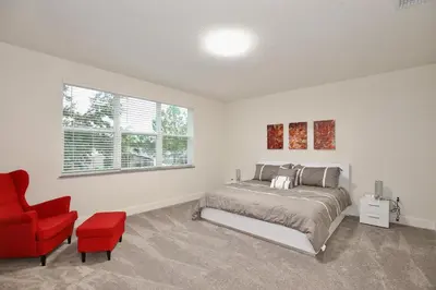 a bedroom with a bed and a red chair at Amazing 3 bedroomloft townhouse in Hidden Forest, with private pool! in Orlando