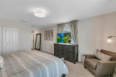 a bedroom with a bed and a couch and a television at 5 Bed Storey Lake Home Lazy River Resort villa in Kissimmee