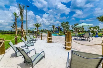 a patio with chairs and tables and a pool at 5 Bed Storey Lake Home Lazy River Resort villa in Kissimmee