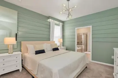 a bedroom with a white bed and green walls at Amazing Game Room Your Kids Will Love! villa in Kissimmee