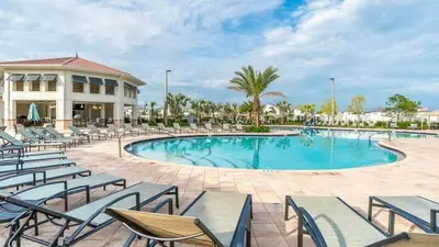 a swimming pool with chairs and a building at Spacious and Luxurious Home With Splash Pool, Close to Disney #4ST804 in Kissimmee