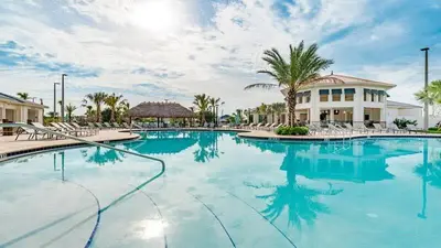 a swimming pool at a resort with chairs and palm trees at Spacious and Luxurious Home With Splash Pool, Close to Disney #4ST804 in Kissimmee