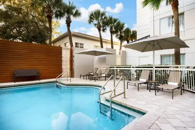 a swimming pool with chairs and umbrellas next to a building at Courtyard by Marriott Orlando Downtown in Orlando