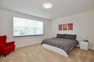 a bedroom with a bed and a red chair at Great 4 bedroom townhouse in Hidden Forest, with private pool! in Orlando