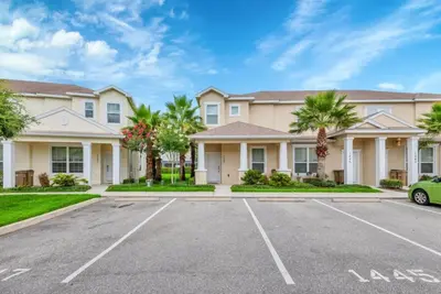a large house with palm trees in a parking lot at Serenity 3 Bed Townhome townhouse in Orlando