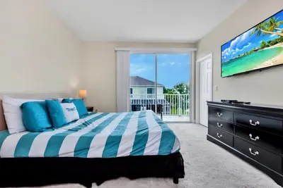a bedroom with a bed and a tv and a balcony at Serenity 3 Bed Townhome townhouse in Orlando