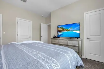 a bedroom with a bed and a flat screen tv at Brand New Storey Lake Resort With Water Slides townhouse in Kissimmee