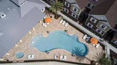 an overhead view of a swimming pool with chairs and umbrellas at Magical Vacation Home 3 min from Disney in Orlando