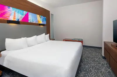 a large white bed in a room with a tv at Aloft Orlando Downtown in Orlando