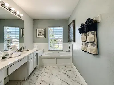 a bathroom with a tub and a sink and a mirror at Luxury Family Villa Pool Hot Tub Close to Disney in Orlando