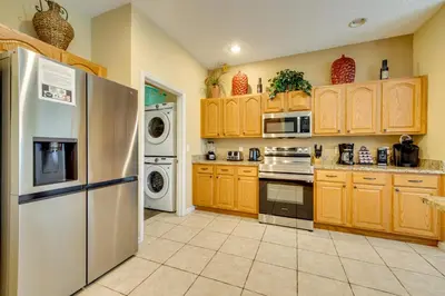 a kitchen with wooden cabinets and a white refrigerator at Spacious Kissimmee Family Home with Game Room and Pool in Kissimmee