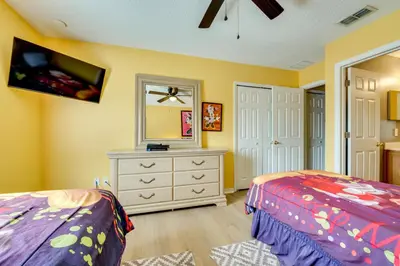 a bedroom with two beds and a dresser with a mirror at Spacious Kissimmee Family Home with Game Room and Pool in Kissimmee