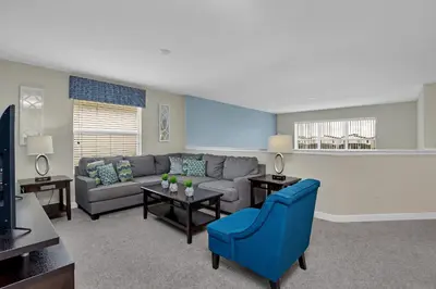 a living room with a couch and a blue chair at LAKEVIEW Home w Private Pool FREE Water Park in Kissimmee